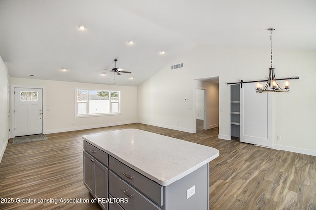 kitchen featuring a barn door, decorative light fixtures, high vaulted ceiling, dark wood-type flooring, and ceiling fan