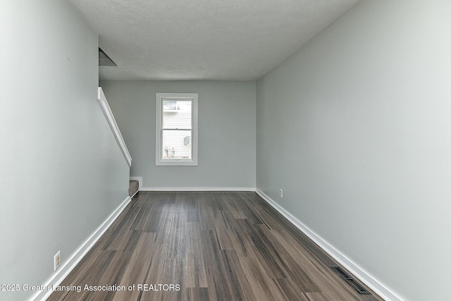 empty room featuring a textured ceiling and dark hardwood / wood-style flooring