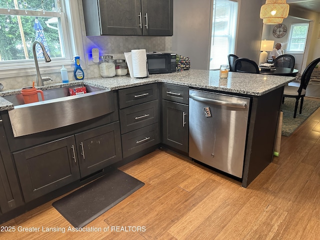 kitchen featuring sink, stainless steel dishwasher, light stone counters, and light hardwood / wood-style floors