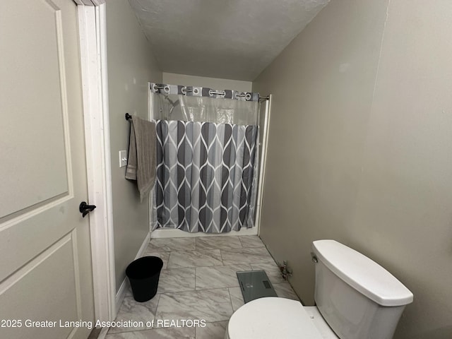 bathroom featuring toilet and curtained shower