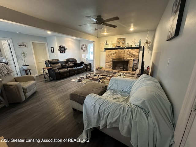 living room featuring wood-type flooring, a brick fireplace, and ceiling fan