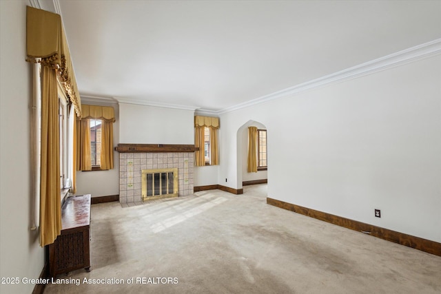 unfurnished living room featuring a tiled fireplace, light colored carpet, and ornamental molding