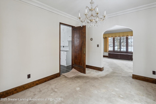 carpeted spare room with crown molding, radiator heating unit, and a notable chandelier