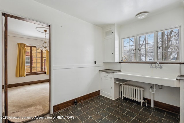 washroom featuring radiator, a wealth of natural light, a chandelier, and dark colored carpet