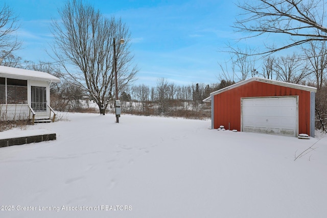 yard layered in snow featuring a garage and an outdoor structure