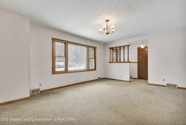 carpeted empty room featuring an inviting chandelier