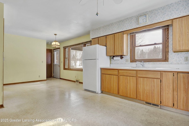 kitchen with white refrigerator, a healthy amount of sunlight, sink, and pendant lighting