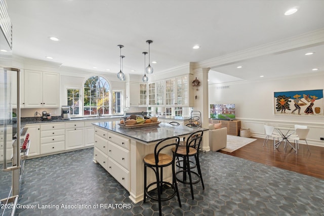 kitchen featuring white cabinetry, a kitchen breakfast bar, crown molding, and a center island