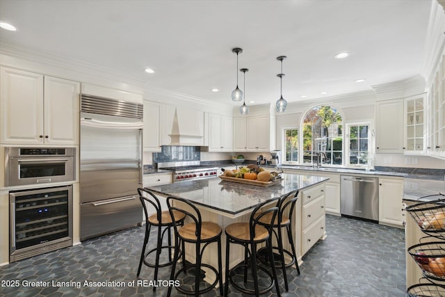 kitchen featuring beverage cooler, appliances with stainless steel finishes, custom exhaust hood, a kitchen bar, and white cabinetry