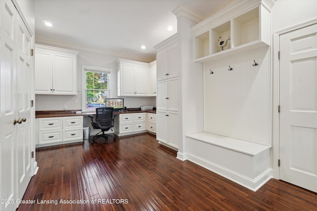 mudroom featuring ornamental molding, built in desk, and dark wood-style floors