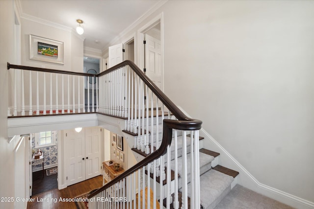 staircase featuring a towering ceiling, baseboards, ornamental molding, and wood finished floors