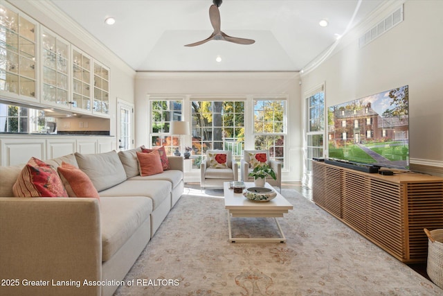 living room with ornamental molding, visible vents, and vaulted ceiling