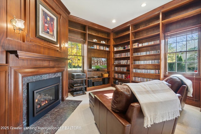 sitting room featuring light carpet, built in shelves, plenty of natural light, and a fireplace