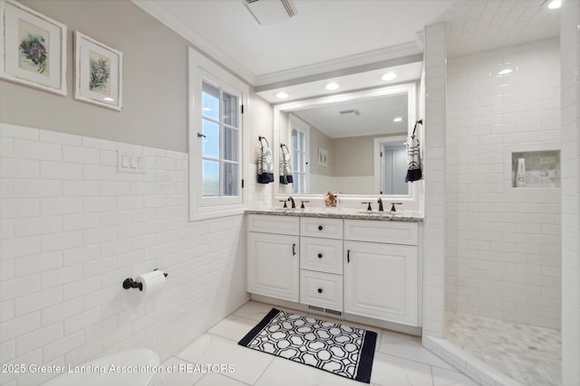 full bath featuring double vanity, ornamental molding, marble finish floor, a walk in shower, and tile walls