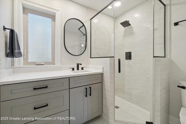 bathroom with toilet, a stall shower, and vanity