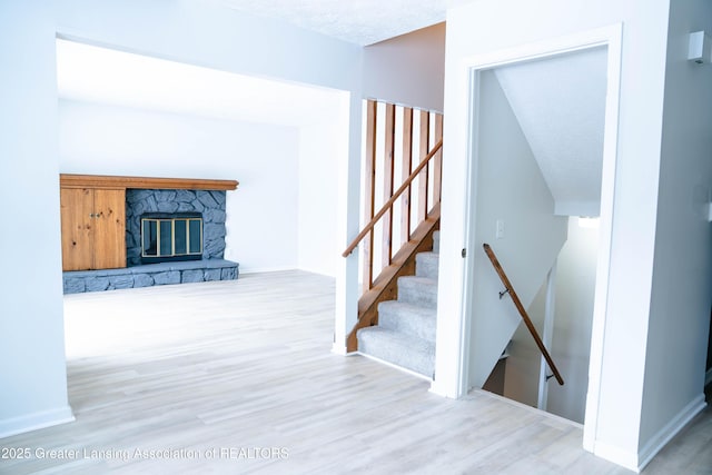 stairway featuring hardwood / wood-style flooring and a stone fireplace