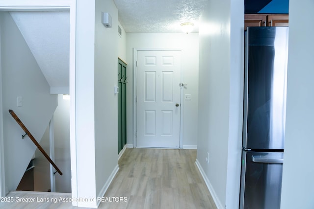 hallway featuring light wood-type flooring and a textured ceiling