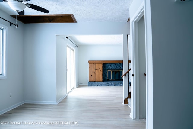 hallway with a textured ceiling and light wood-type flooring