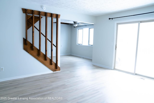 spare room featuring ceiling fan, a textured ceiling, and light hardwood / wood-style flooring