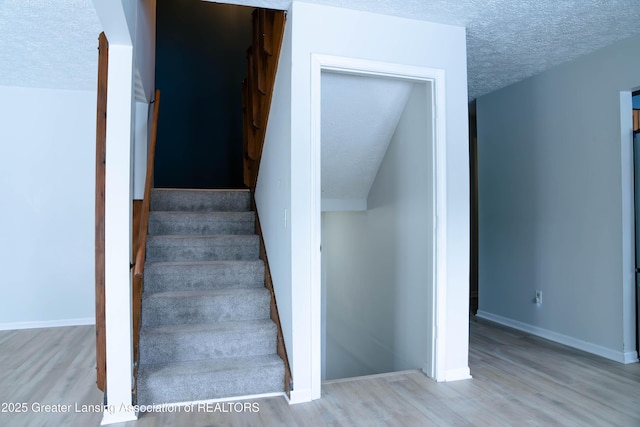 staircase with hardwood / wood-style flooring and a textured ceiling