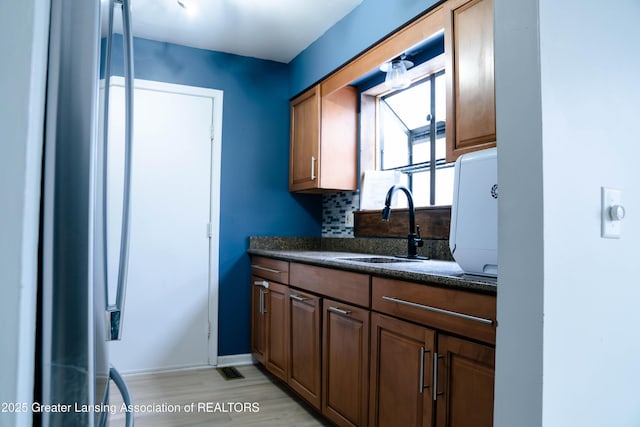 kitchen with light hardwood / wood-style floors, sink, and backsplash