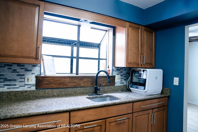 kitchen featuring light stone counters, sink, and decorative backsplash