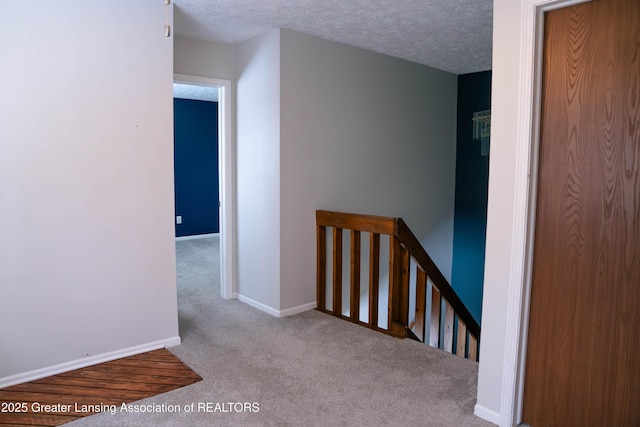 hall featuring light colored carpet and a textured ceiling