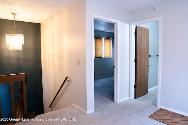 hallway featuring light colored carpet and a textured ceiling