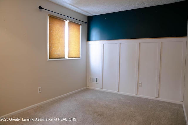 empty room featuring light carpet and a textured ceiling