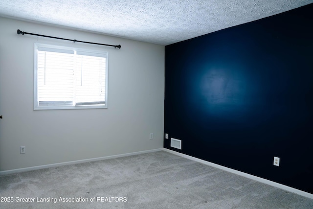 unfurnished room featuring light carpet and a textured ceiling