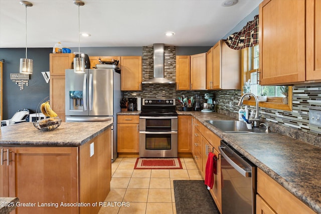 kitchen featuring a kitchen island, decorative light fixtures, sink, stainless steel appliances, and wall chimney range hood