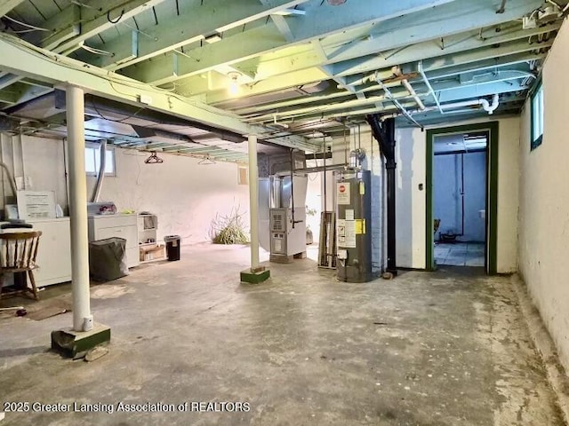 basement featuring water heater, washing machine and dryer, and heating unit