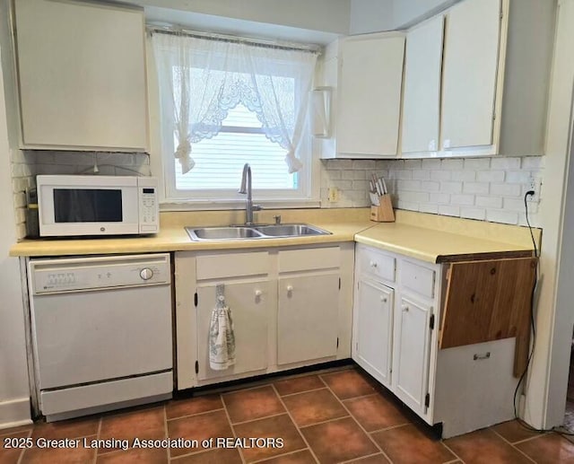 kitchen featuring tasteful backsplash, white cabinetry, sink, dark tile patterned floors, and white appliances