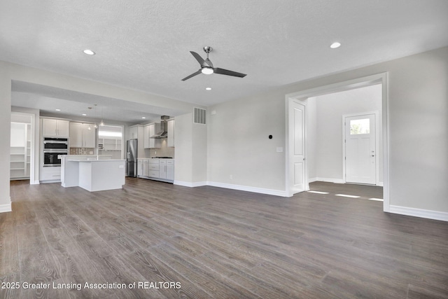 unfurnished living room with wood-type flooring, a textured ceiling, and ceiling fan