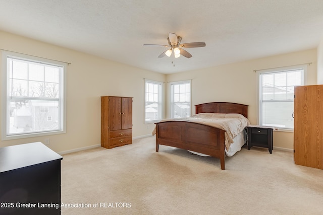 bedroom with light carpet, ceiling fan, multiple windows, and baseboards