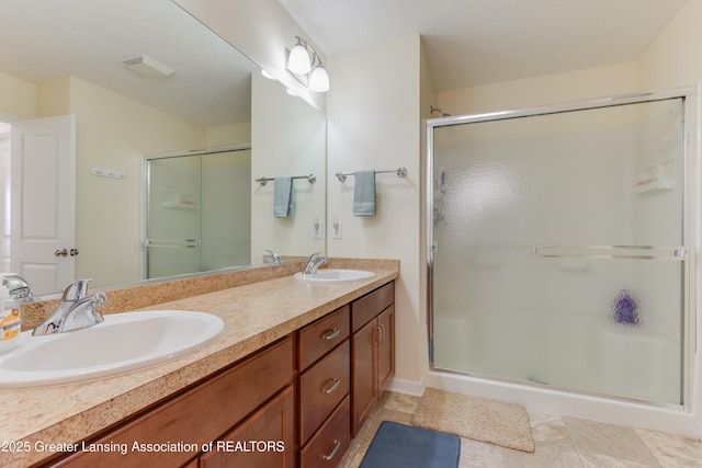 full bath with double vanity, a stall shower, and a sink