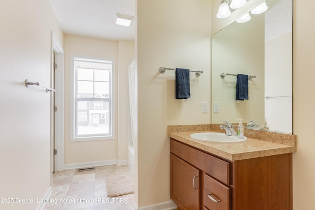 bathroom featuring shower / bath combo, vanity, visible vents, and baseboards