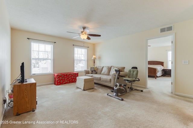 carpeted living area featuring visible vents, ceiling fan, a textured ceiling, and baseboards