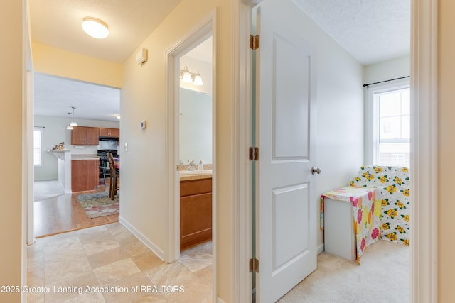 hallway with a sink, baseboards, and a textured ceiling