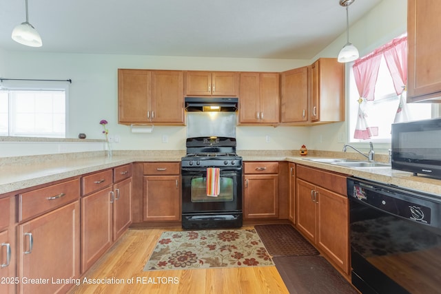 kitchen featuring black appliances, hanging light fixtures, light wood-type flooring, and under cabinet range hood