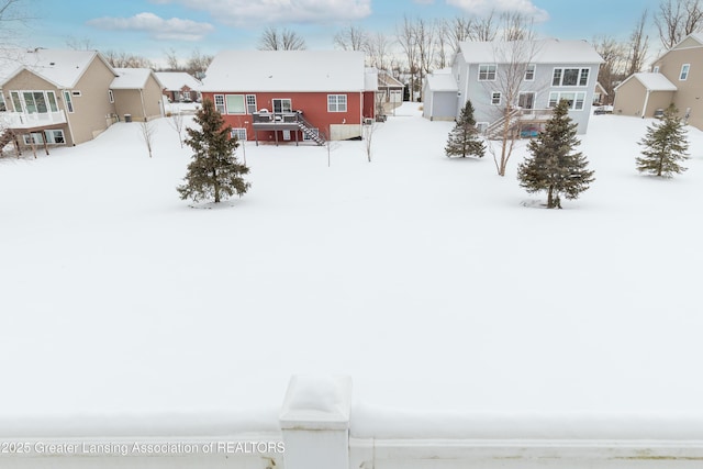 snowy yard featuring a deck and a residential view