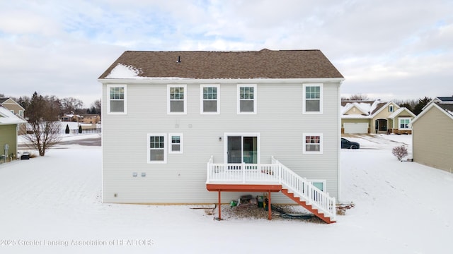 snow covered rear of property with a deck and stairs