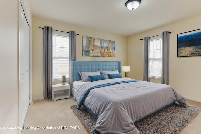 bedroom with multiple windows, light carpet, and baseboards