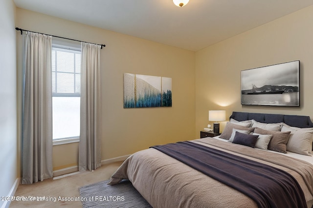 bedroom featuring light colored carpet and baseboards