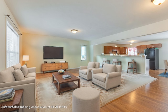 living area featuring light wood-style flooring and baseboards