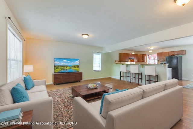 living area with baseboards and light wood finished floors