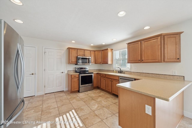 kitchen featuring appliances with stainless steel finishes, kitchen peninsula, sink, and light tile patterned floors