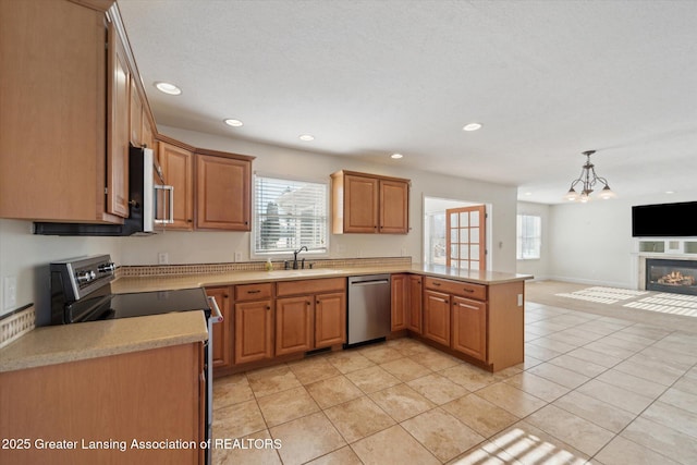 kitchen featuring stainless steel appliances, light tile patterned flooring, hanging light fixtures, and sink