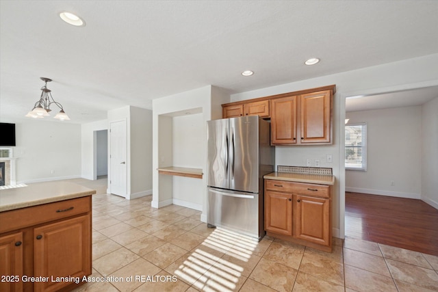 kitchen featuring light tile patterned floors, stainless steel refrigerator, and decorative light fixtures