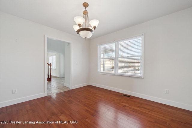 spare room featuring a chandelier and hardwood / wood-style floors